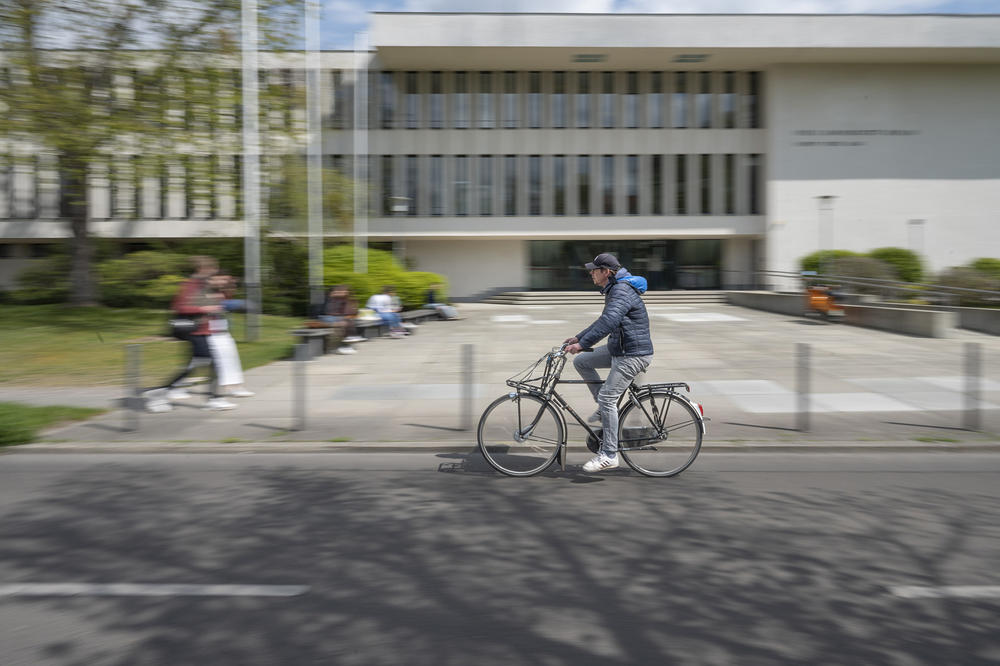 Ein Fahrradfahrer vor dem Gebäude der Universitätsbibliothek
