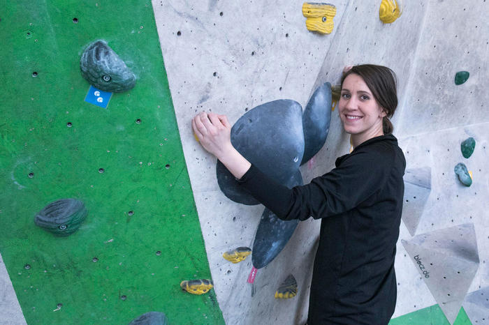 Person in front of a climbing wall smiling at the camera